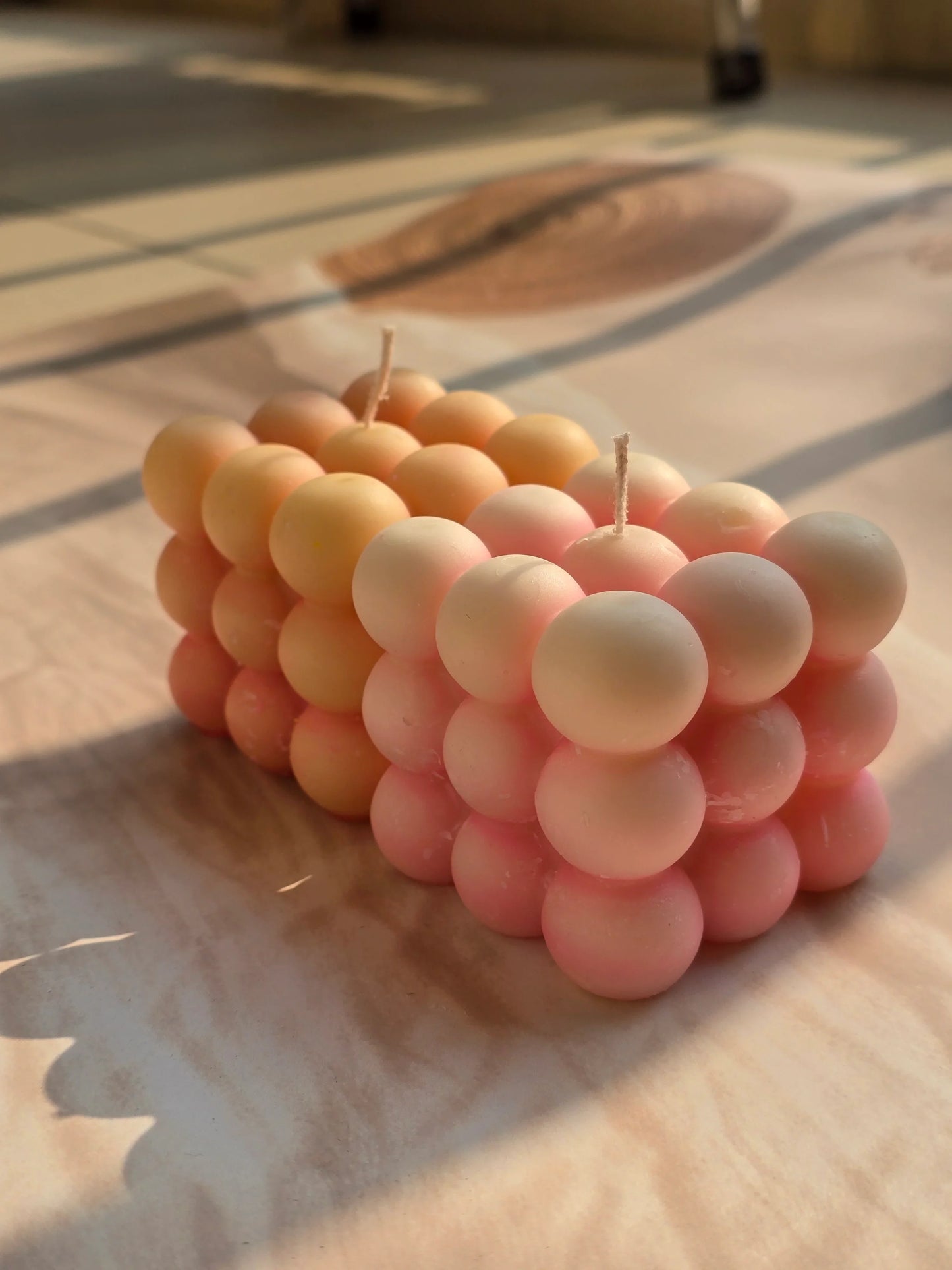 Pink and peach bubble soy wax candles from Fiorance Luxe on sunlit marble surface