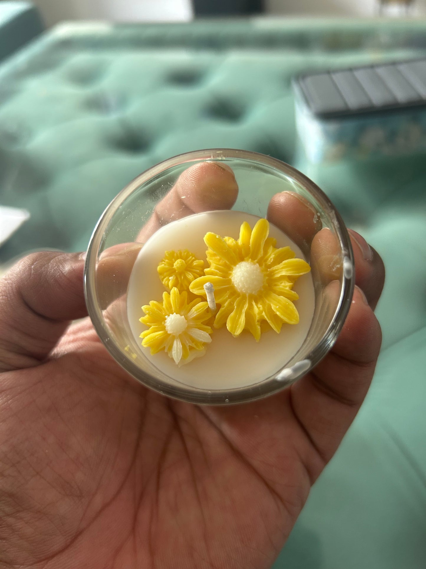Hand holding Fiorance Luxe soy wax floral candle with yellow daisy designs in glass jar