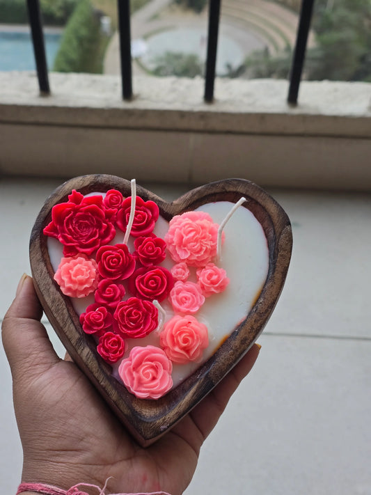 Hand holding a heart-shaped soy wax floral candle by Fiorance Luxe with pink and red roses