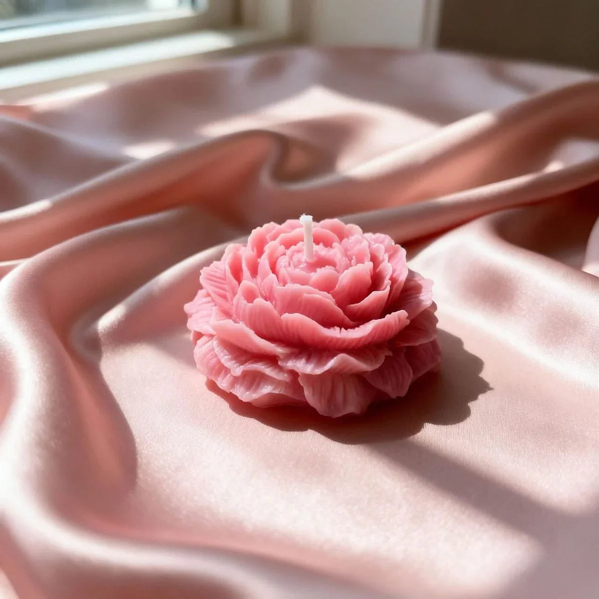 Pink floral soy wax candle on silky blush fabric, Fiorance Luxe premium home decor.