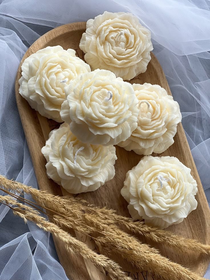 Wooden tray with white flower-shaped soap pieces on a light gray background