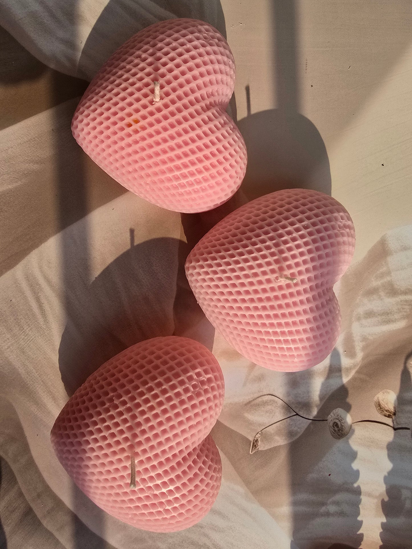 Three pink heart-shaped sponges on a wooden surface