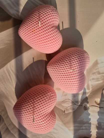 Three pink heart-shaped sponges on a wooden surface