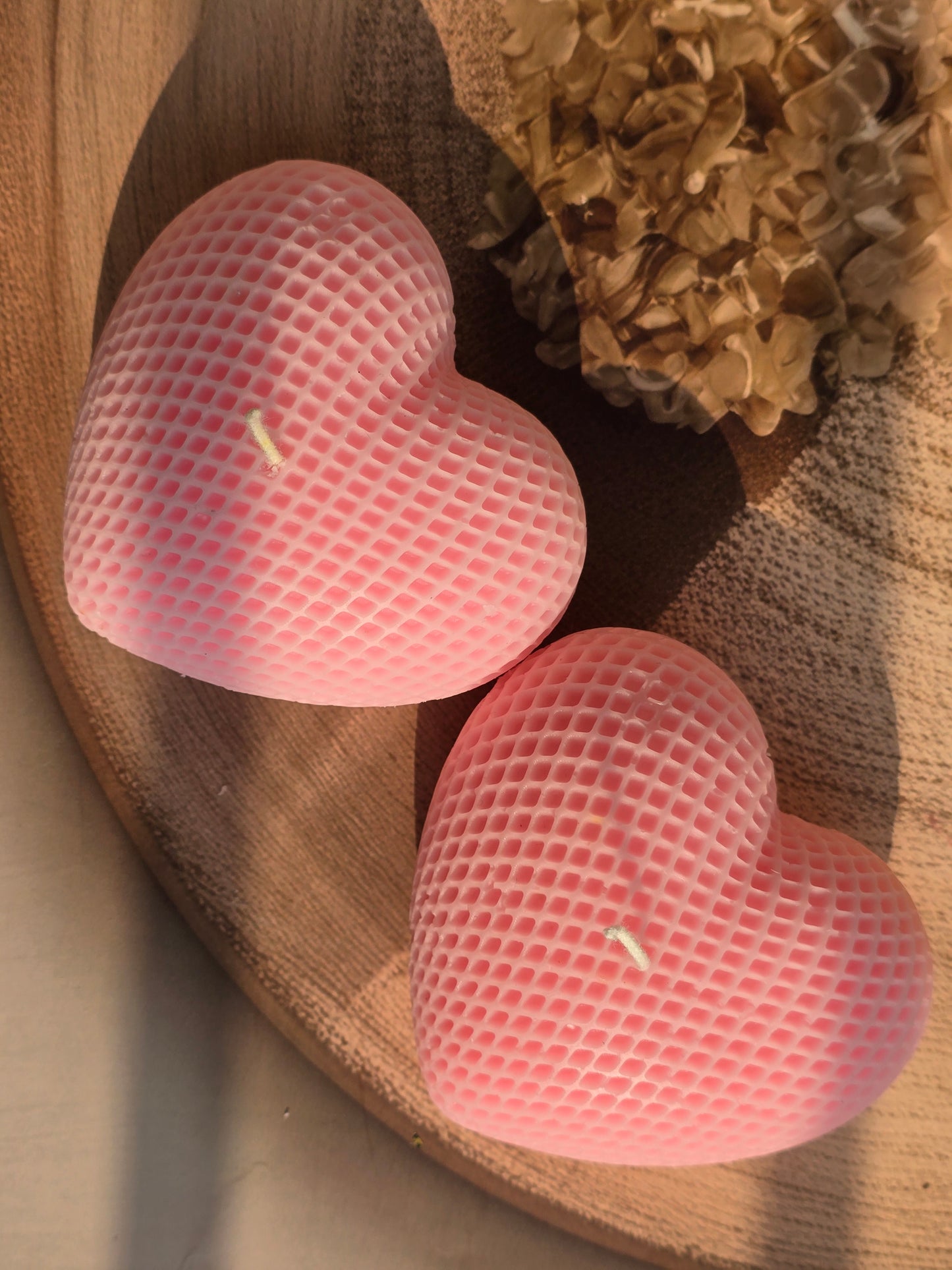 Two pink textured heart-shaped objects on a wooden surface
