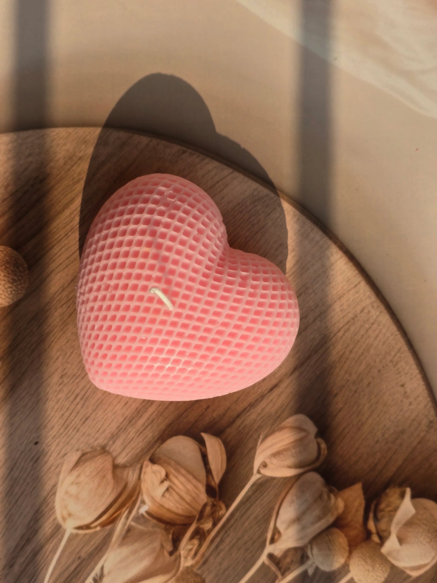 Pink textured ball on a wooden surface with dried plants