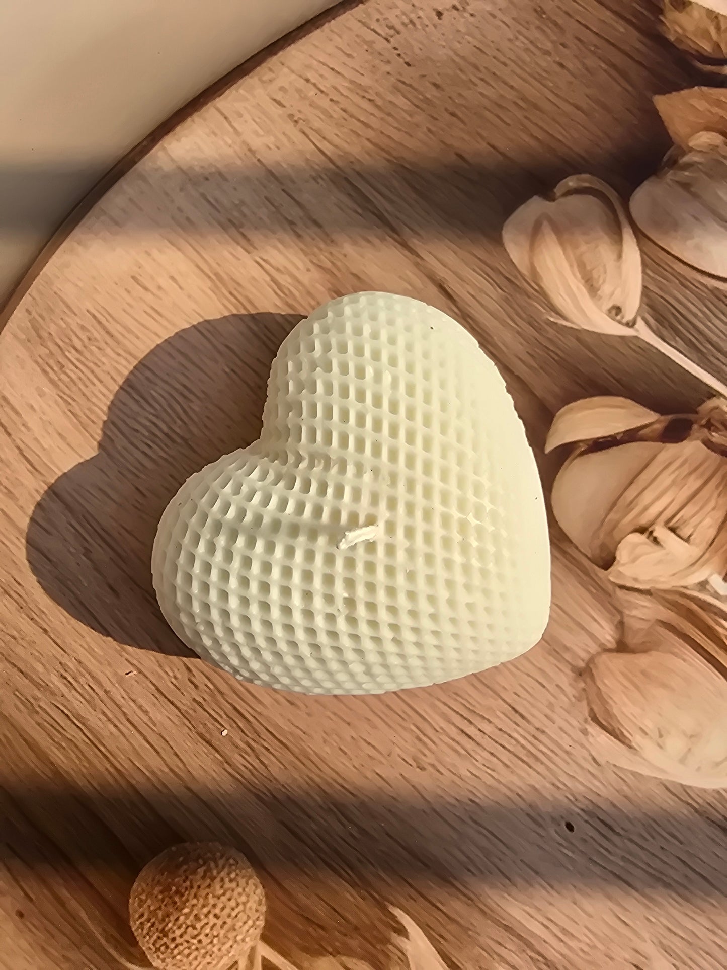 Heart-shaped candle with textured surface on a wooden surface