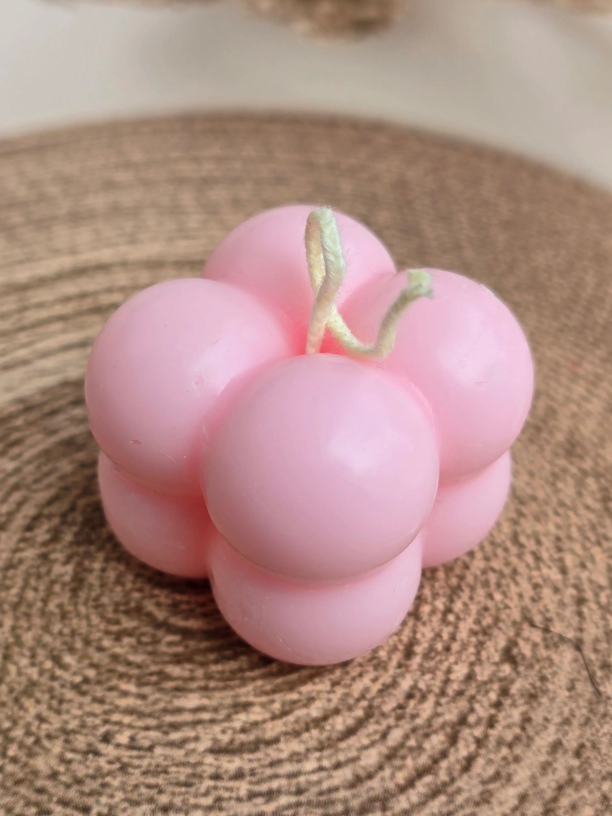 Pink bubble-shaped soy wax candle from Fiorance Luxe on a woven mat