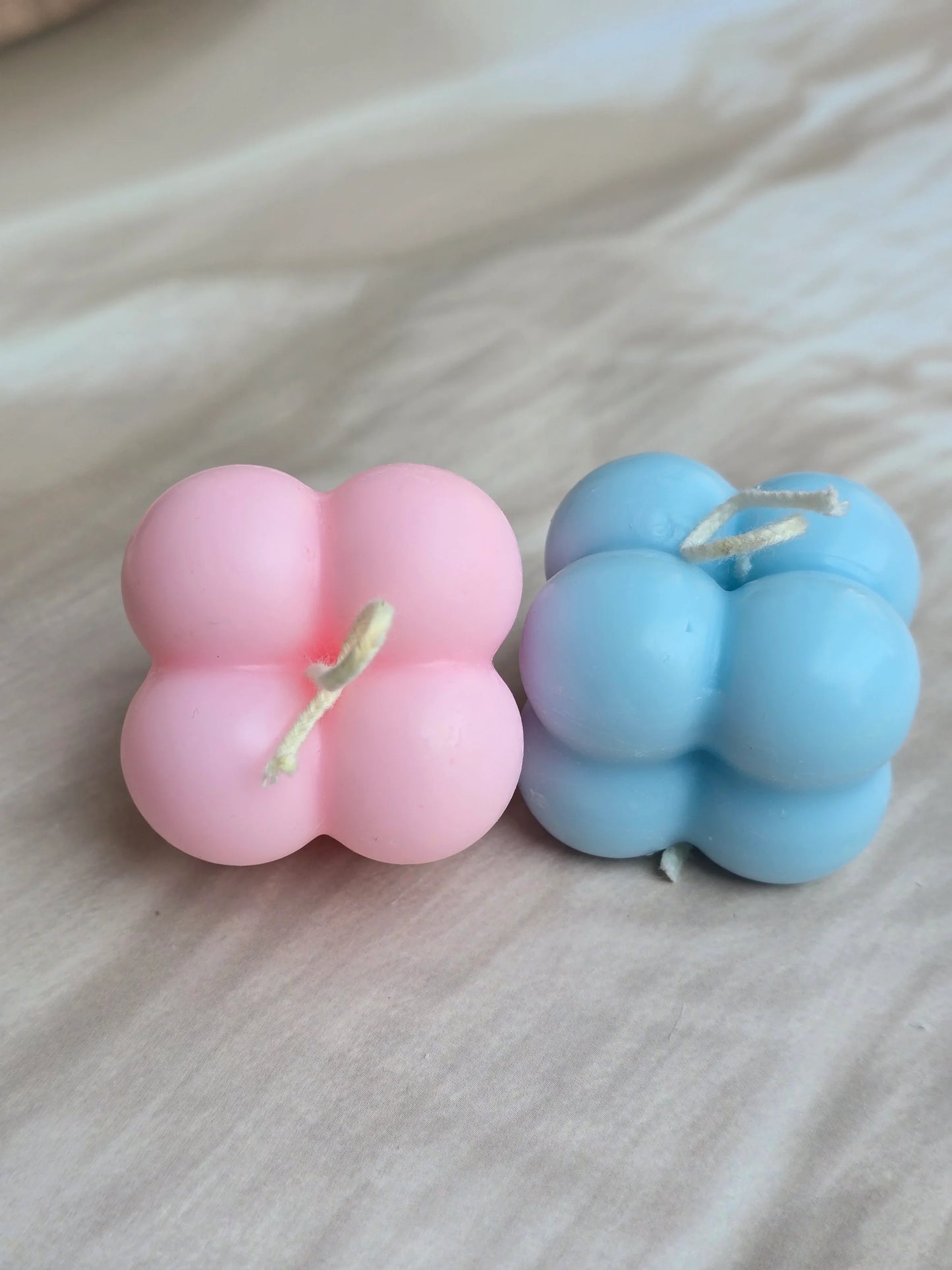 Pink and blue bubble soy wax candles from Fiorance Luxe on a light surface