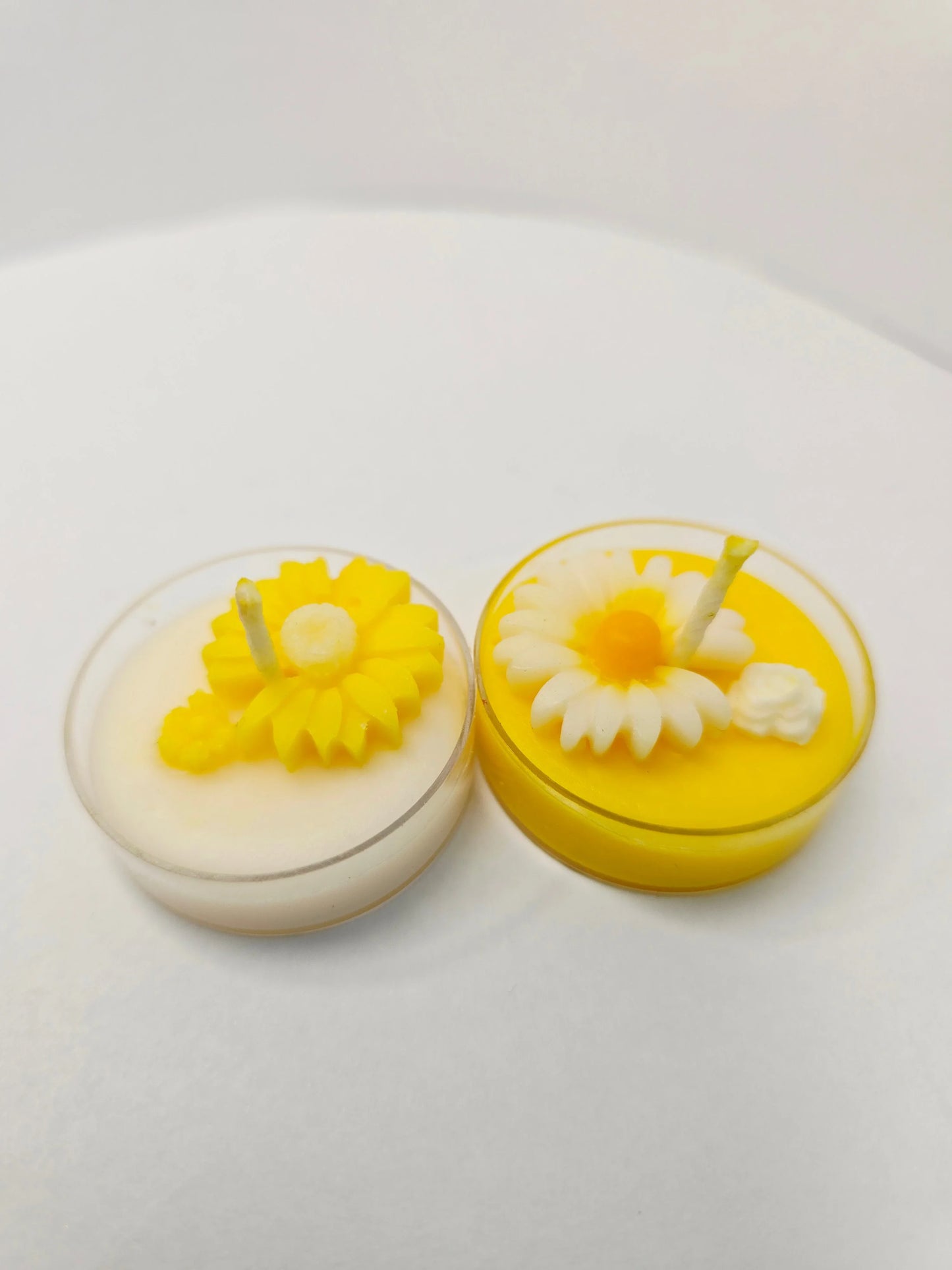 Two Fiorance Luxe floral soy wax candles with daisy designs in small round containers