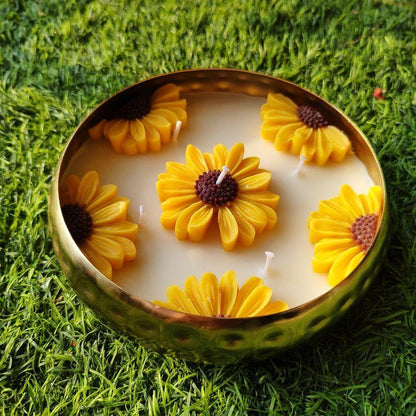 Candle with sunflower design in a decorative bowl or urli