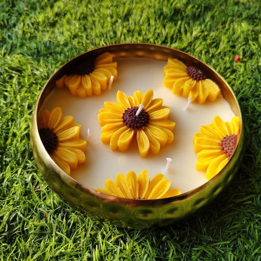 Candle with sunflower design in a decorative bowl or urli
