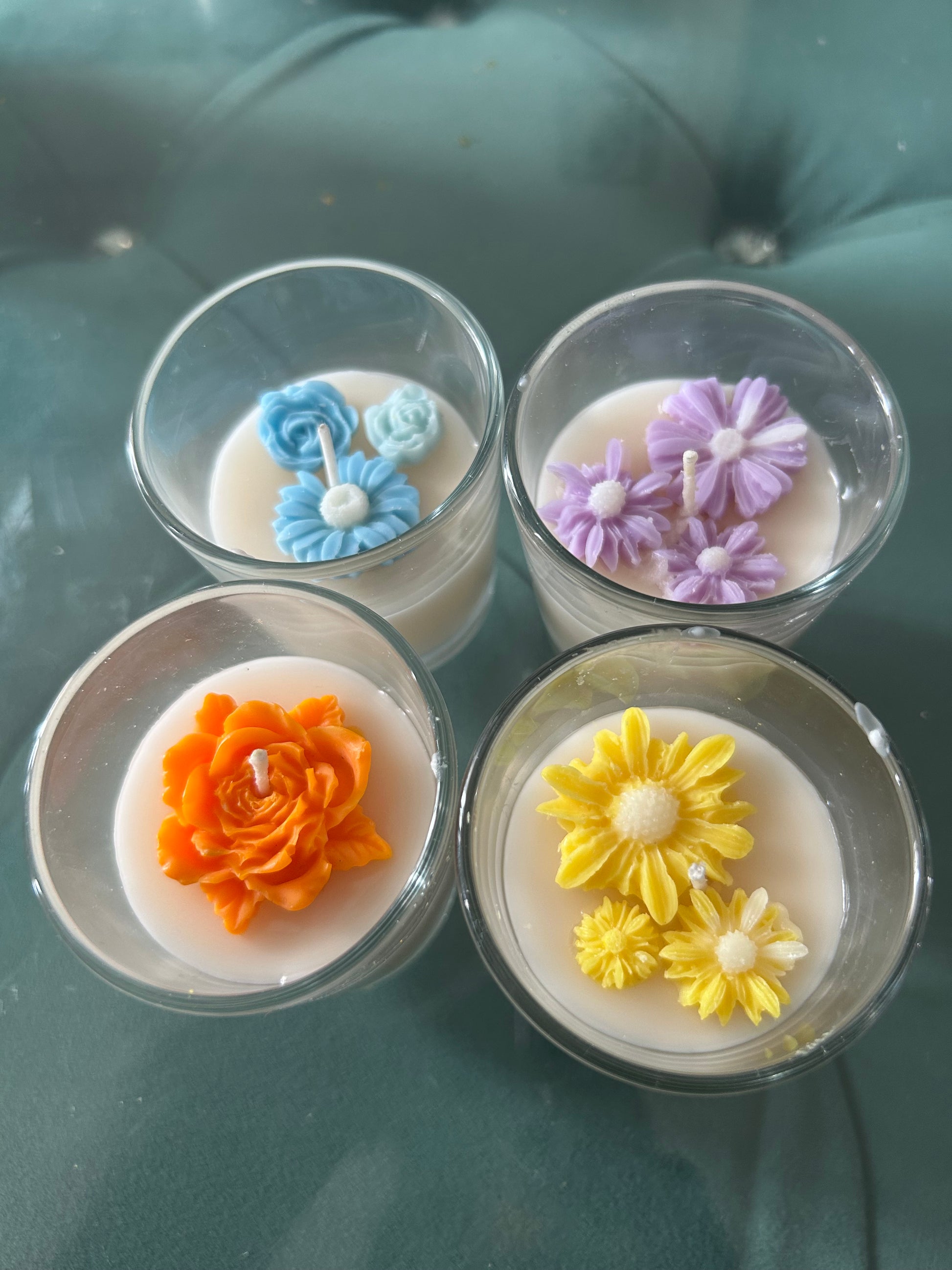 Four Fiorance Luxe soy wax candles with colorful floral designs in glass jars on a soft surface.