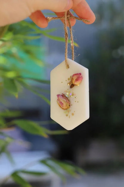Hand holding Fiorance Luxe floral soy wax scented hanging tablet with dried rosebuds