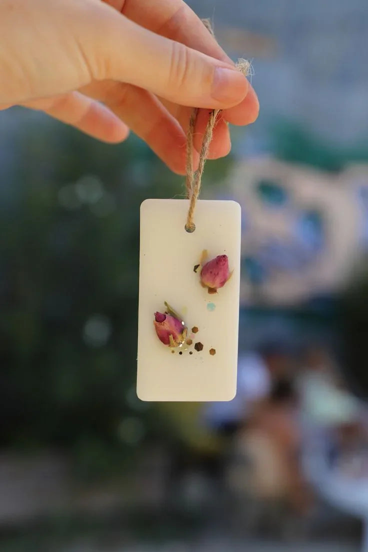 Hand holding Fiorance Luxe soy wax scented suspension with dried rosebuds for home decor