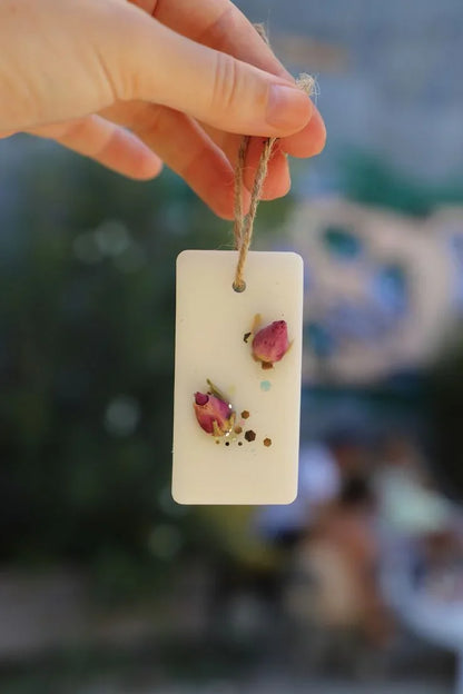 Hand holding Fiorance Luxe soy wax scented suspension with dried rosebuds for home decor