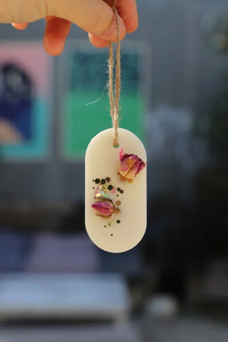 Hand holding oval scented wax sachet with dried rosebuds and glitter by Fiorance Luxe