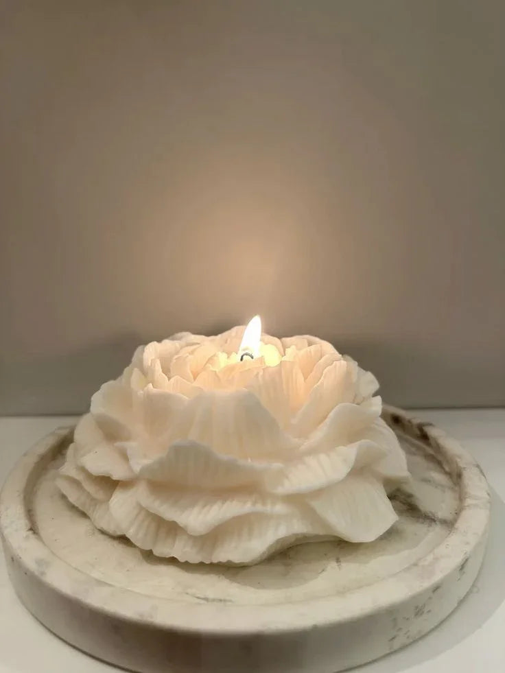 Floral-shaped candle on a white surface with a neutral background