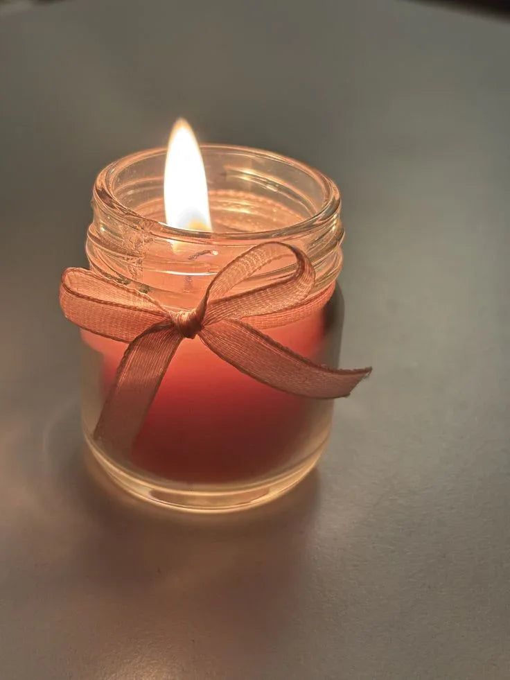 Lit pink soy wax candle in glass jar with ribbon, Fiorance Luxe luxury scented candle