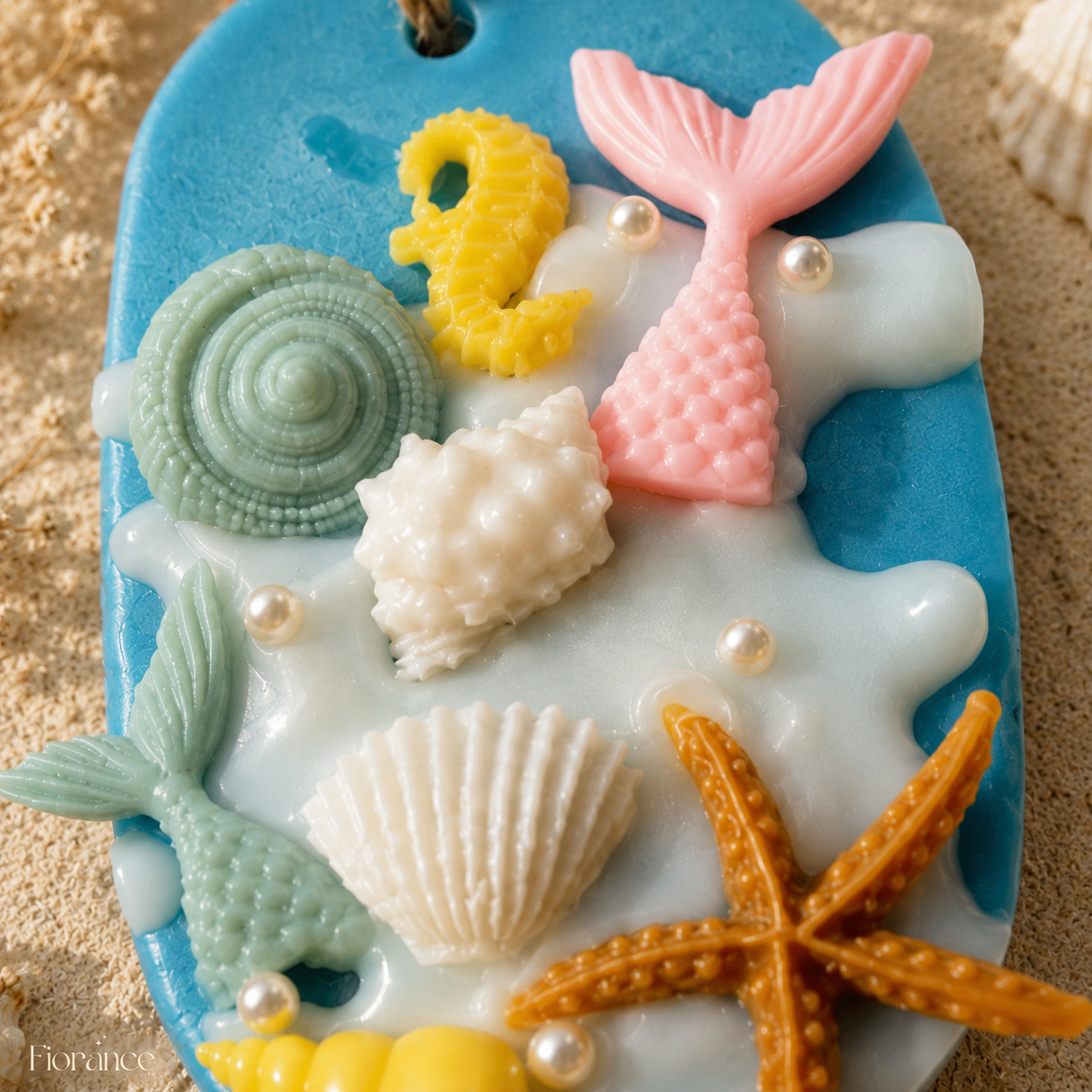 Close-up of the Mermaid Ocean wax sachet showing the pink mermaid tail, yellow seahorse, sculpted shells and pearl details.