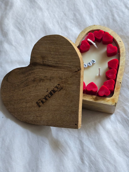 Wooden heart-shaped box with a candle and red hearts on a white fabric background