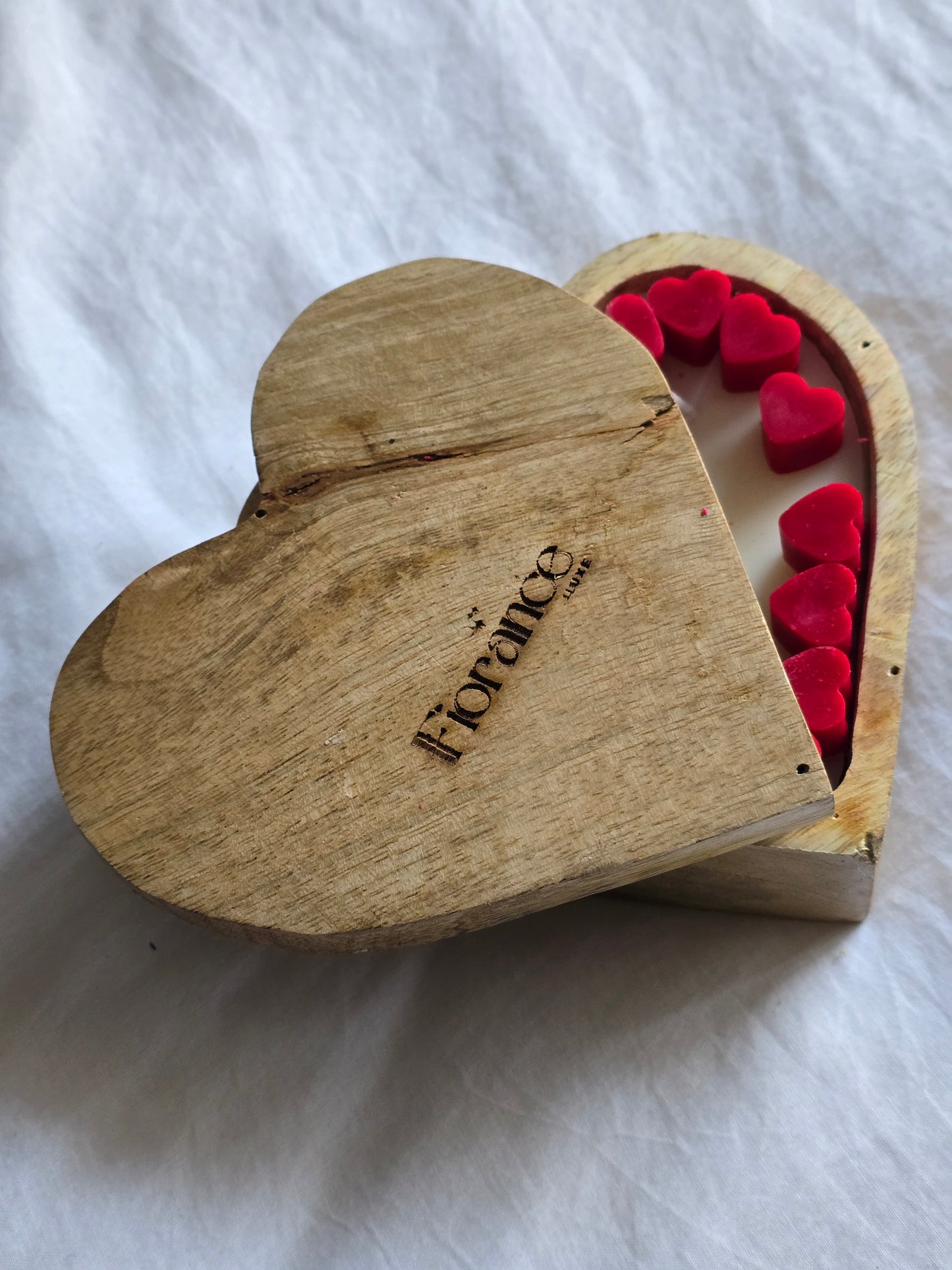 Heart-shaped wooden box with red hearts inside on a white background