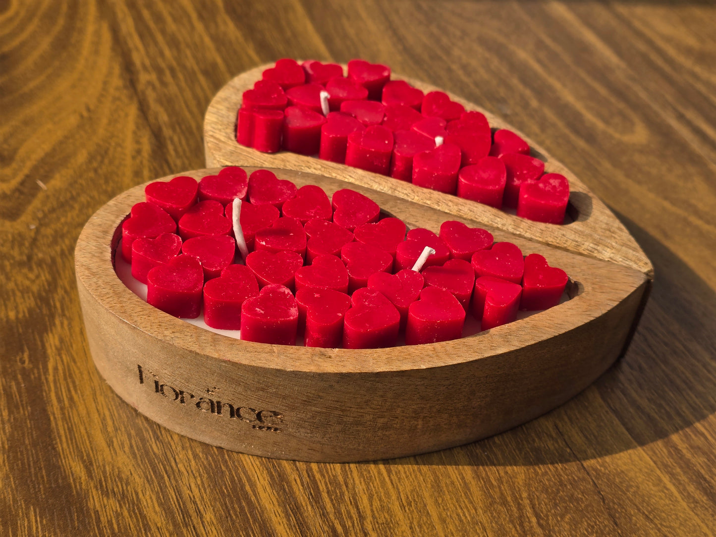 Heart-shaped wooden candle holder with red candles on a wooden surface