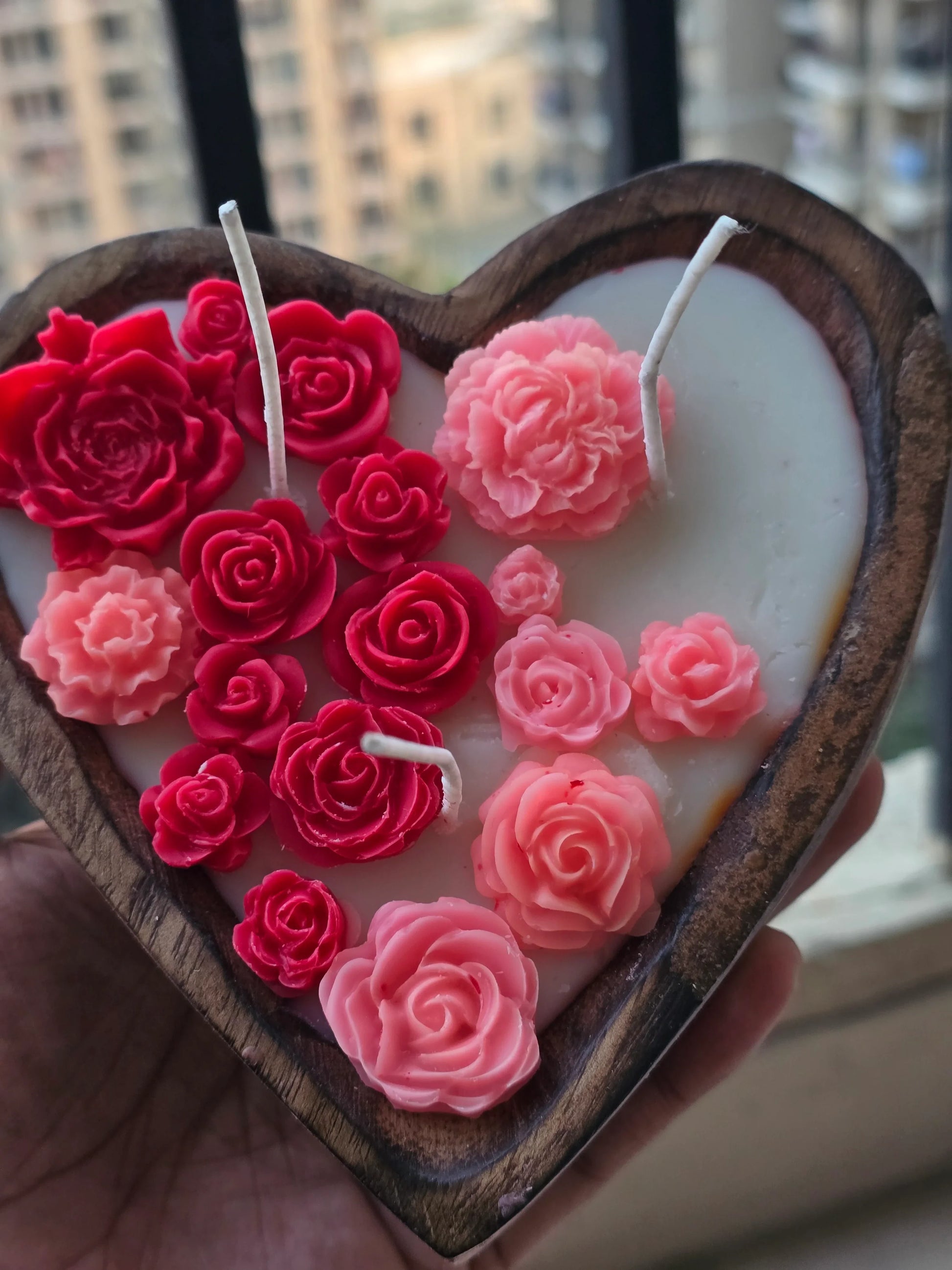 Heart-shaped Fiorance Luxe soy wax candle with pink and red floral designs in a wooden holder