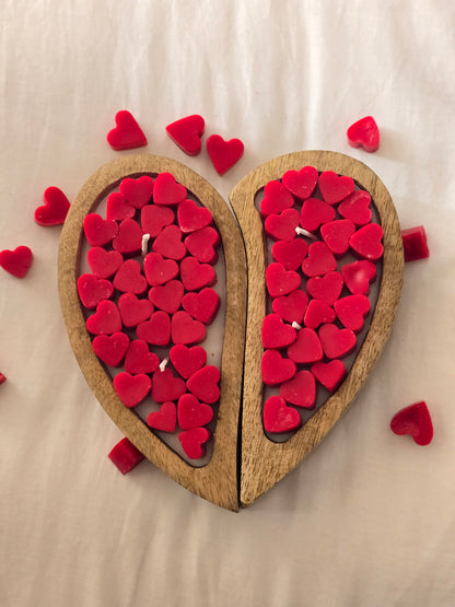 Wooden heart-shaped box filled with red heart-shaped objects on a beige background