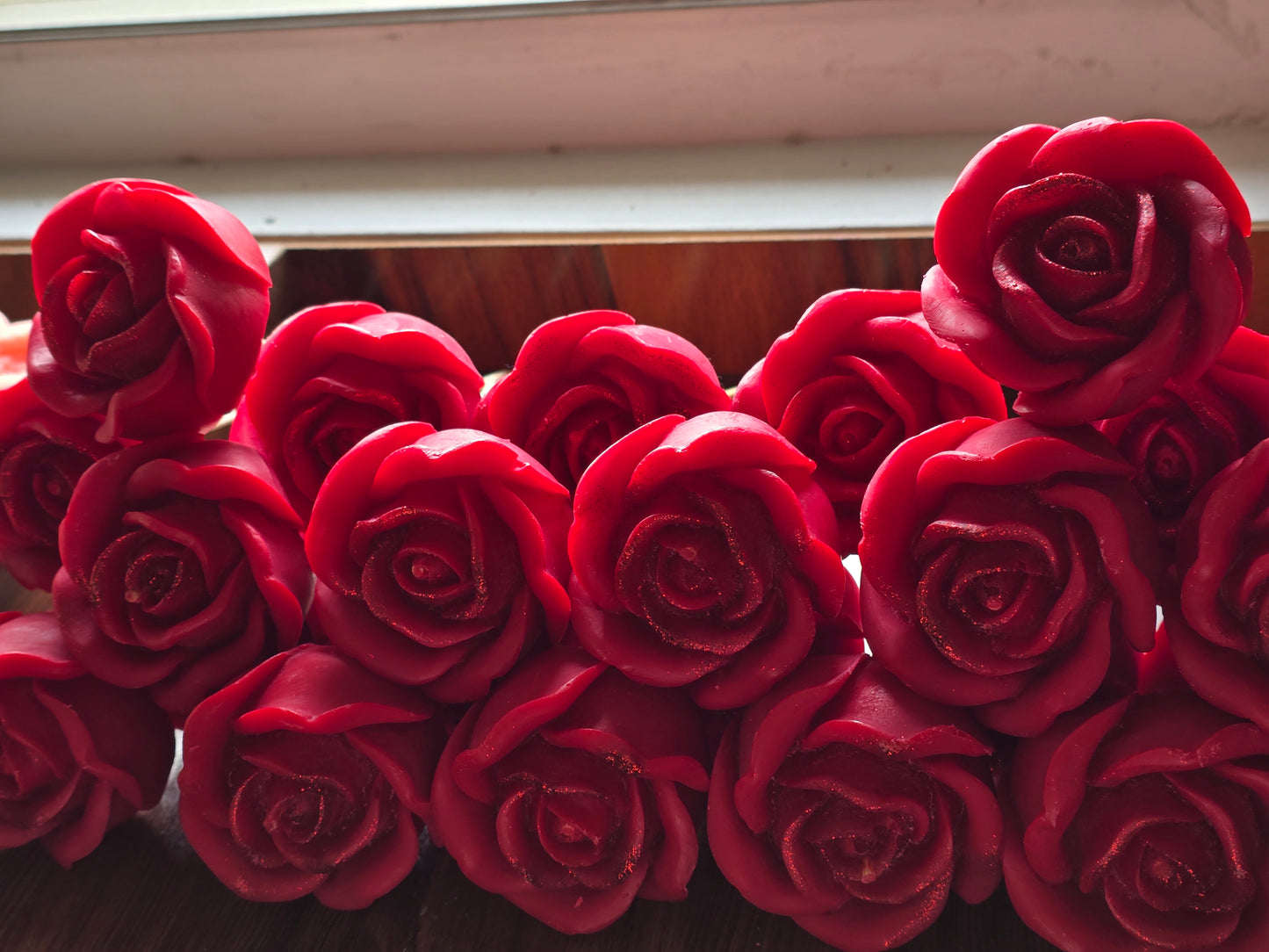 Handcrafted red rose-shaped soy wax candles by Fiorance Luxe near a window
