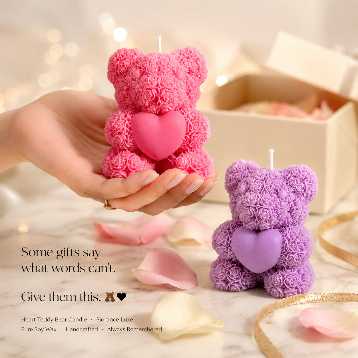 Pink and purple teddy bear candles held by a hand with blurred lights in the background.