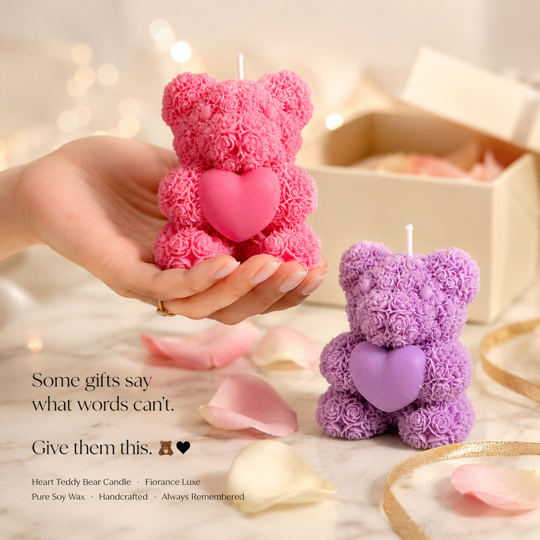 Pink and purple teddy bear candles held by a hand with blurred lights in the background.