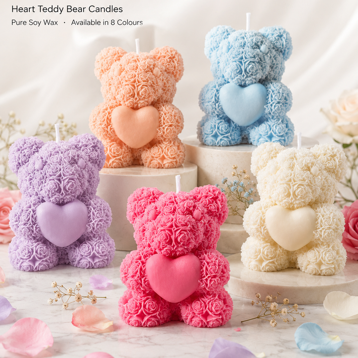 Heart-shaped teddy bear candles in various colors on a marble surface with flowers.