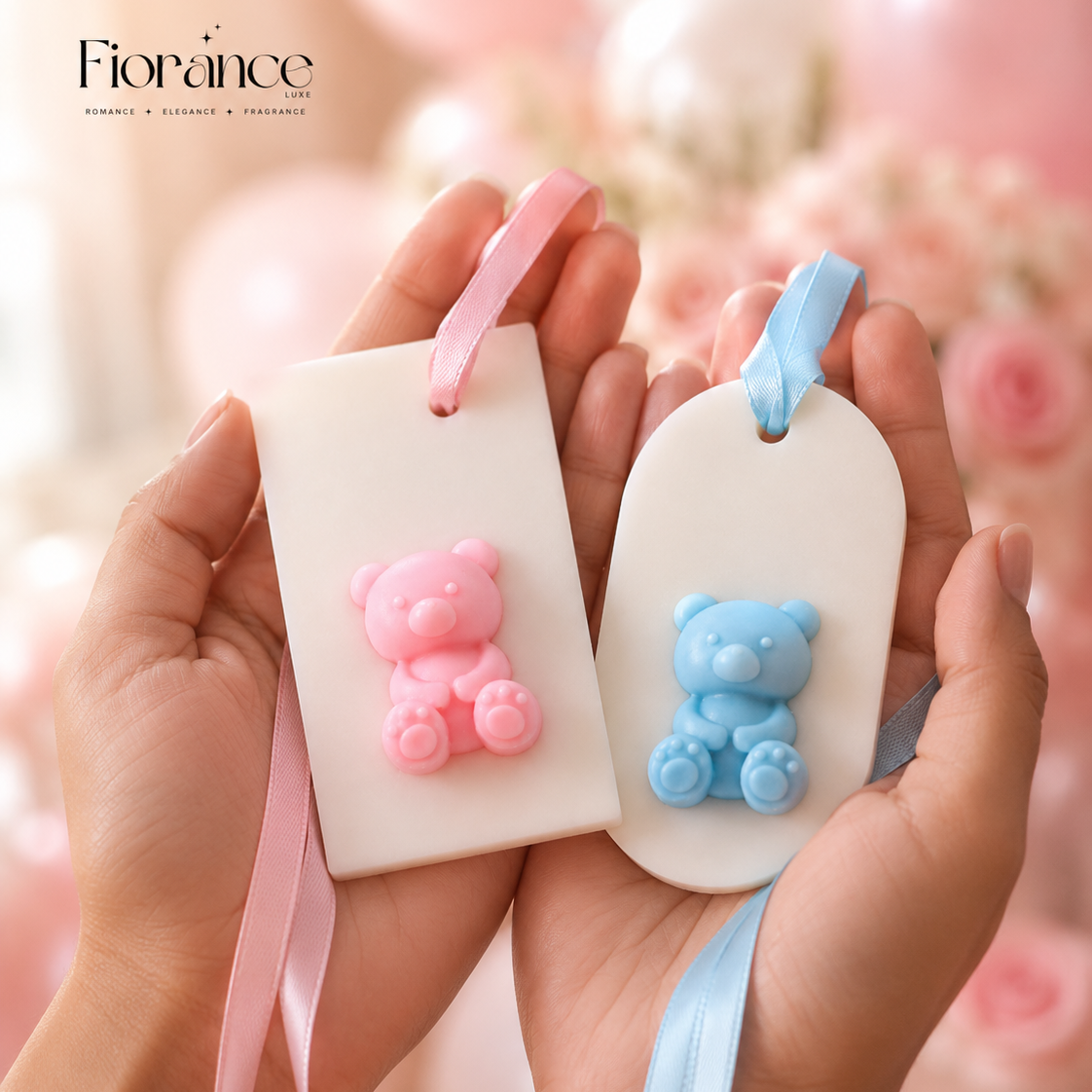 Two small bear-shaped wax sachet with ribbons held in hands against a blurred background.