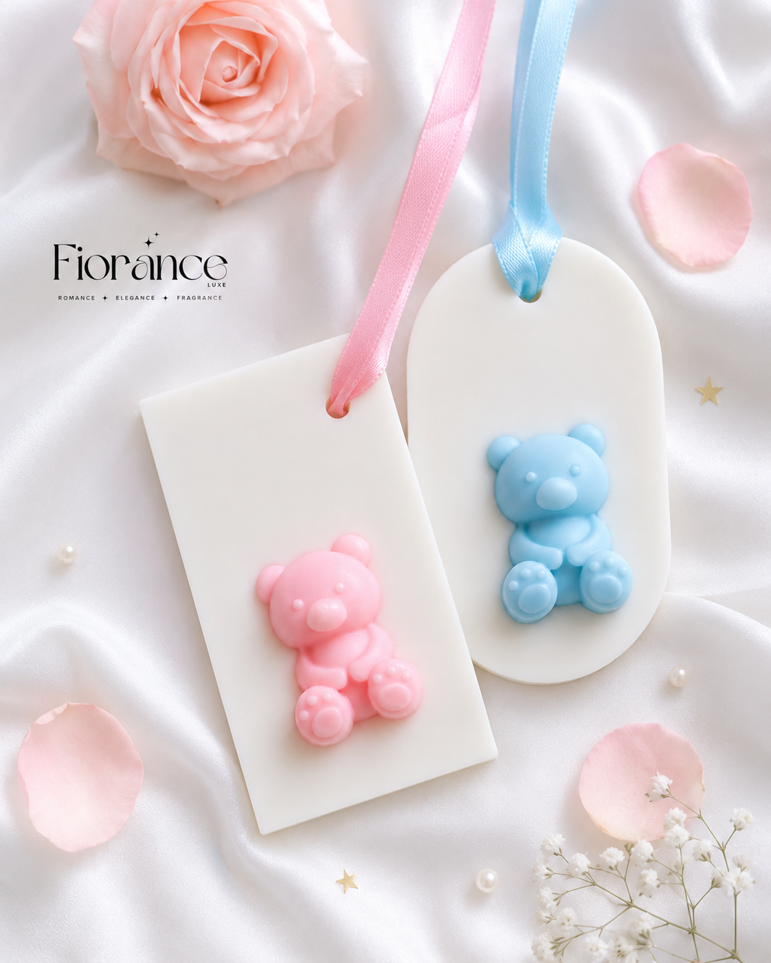 Two bear-shaped wax sachets on white tags with pink and blue ribbons, surrounded by pink roses and petals.